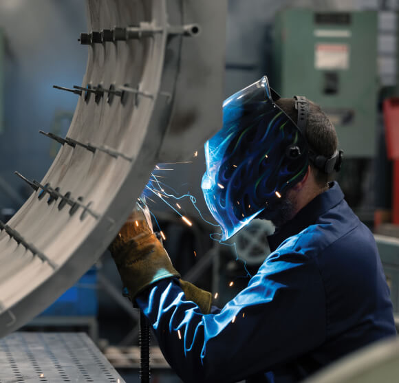 VESCO A company of the BUSCH Group A welder working on a piece of metal in a factory.